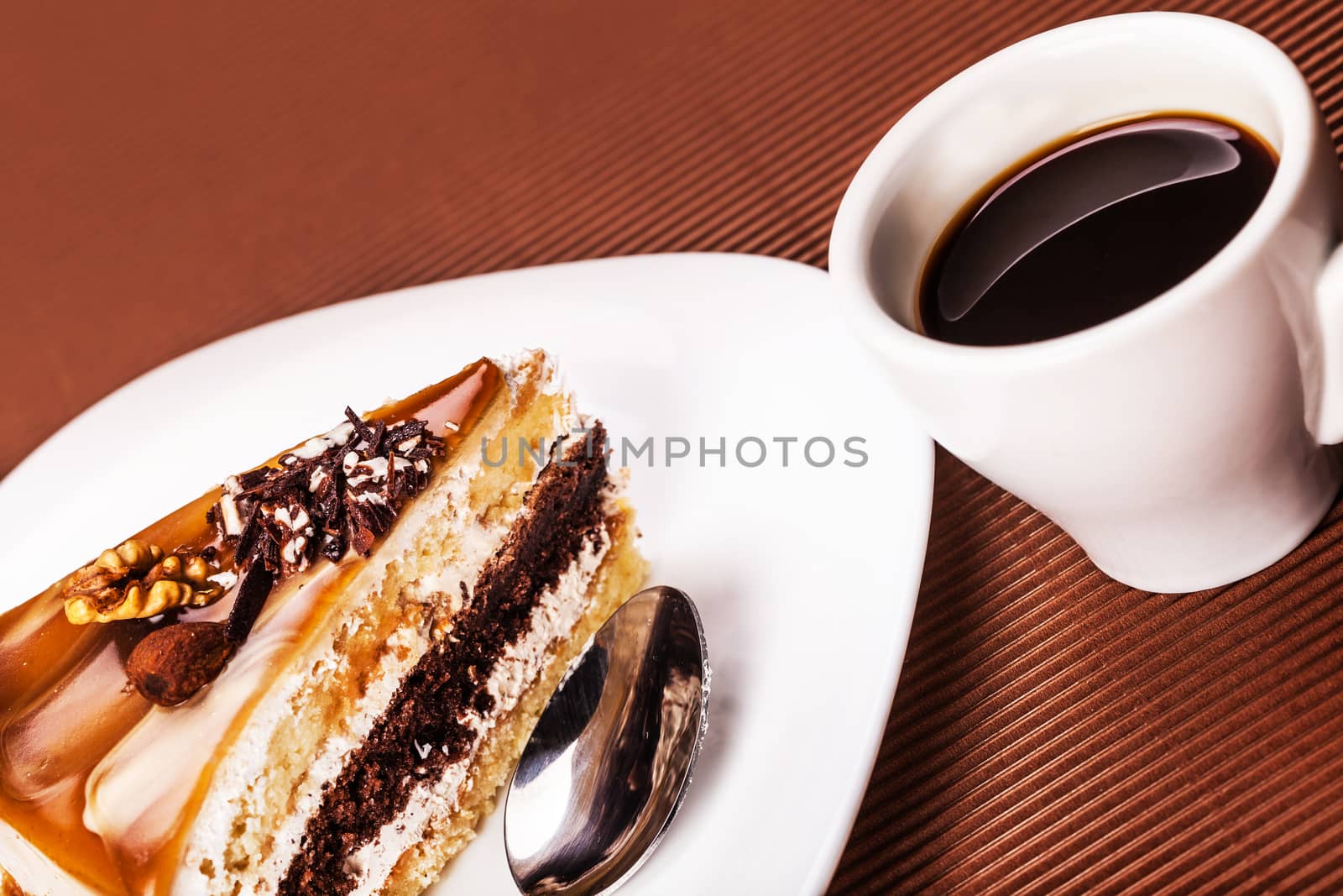 piece of walnut cake and a cup of coffee on a brown background