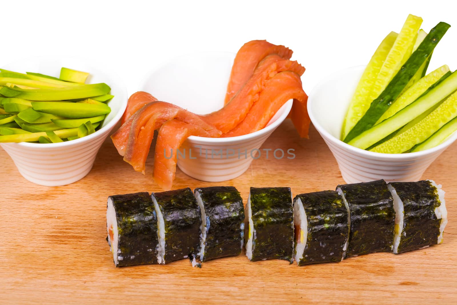 avocado, cucumber, fish and rolls on a wooden board