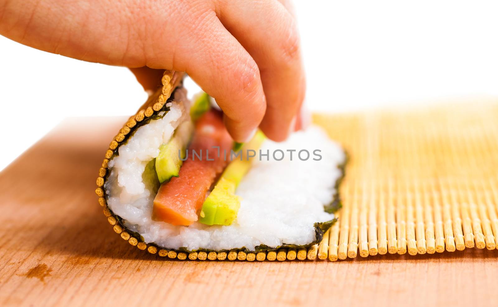 chef turns nori sheet with filling in the roll