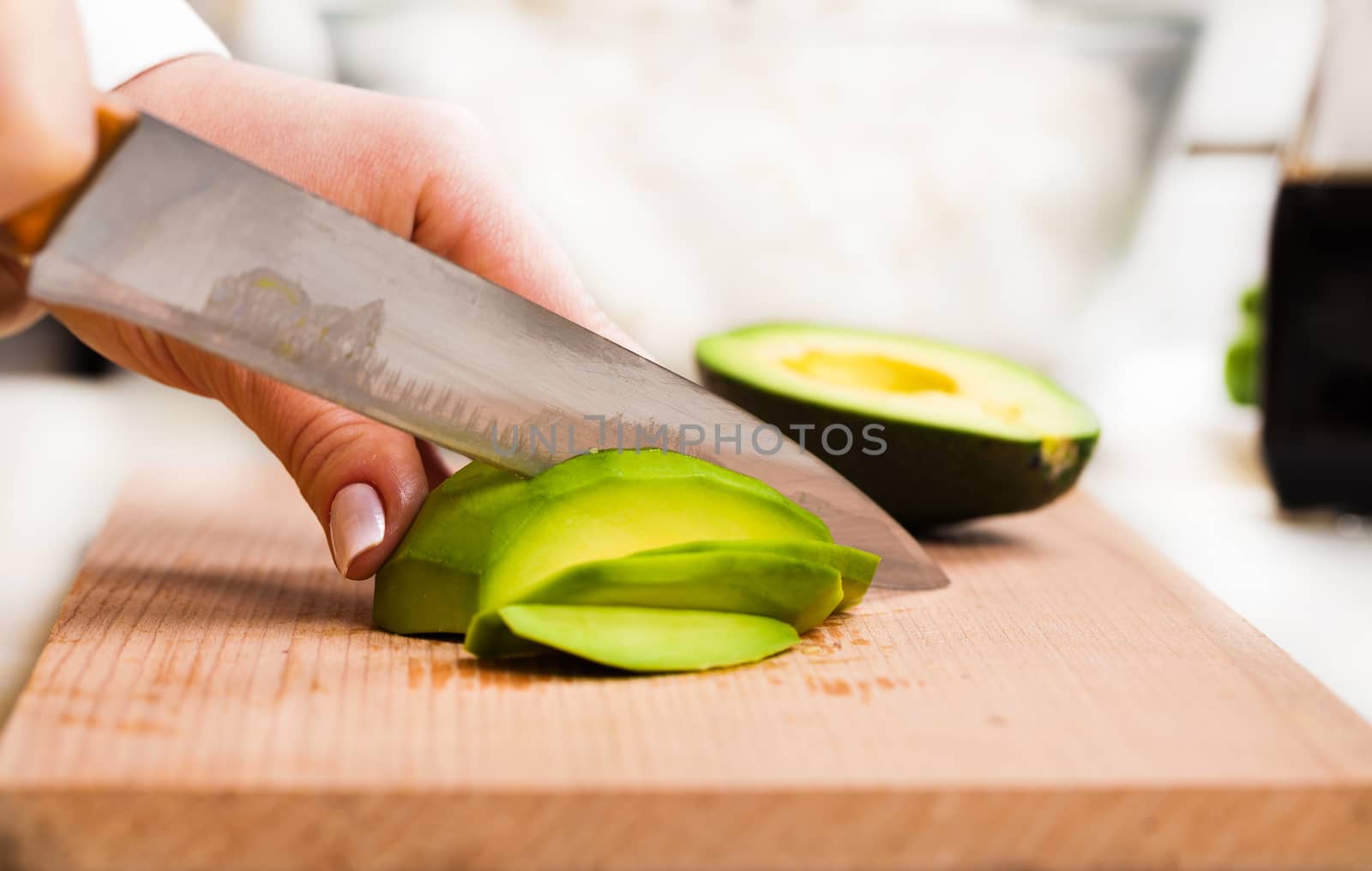 chef slicing the avocado close-up on a wooden board