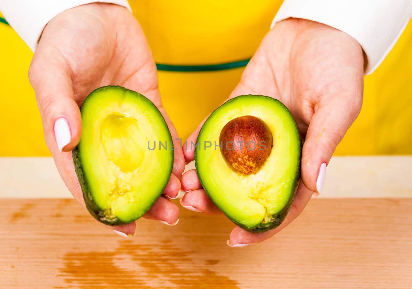 chef holds two pieces of fresh avocado closeup