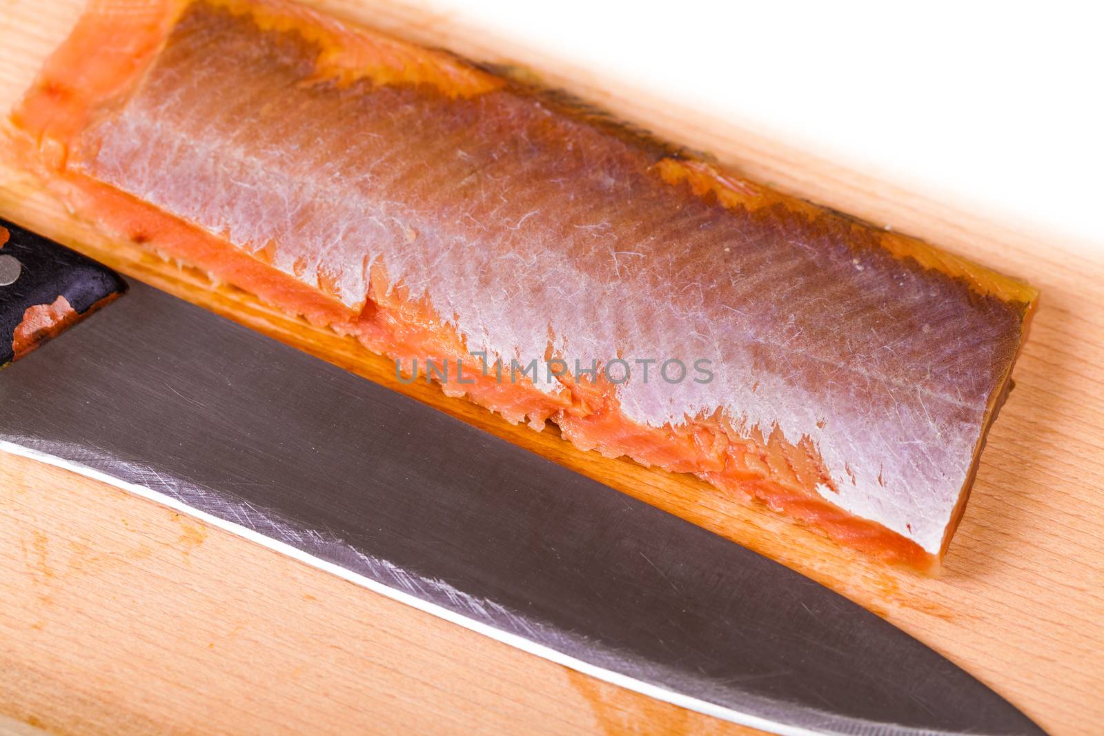 red fish fillet and knife close-up on a wooden board