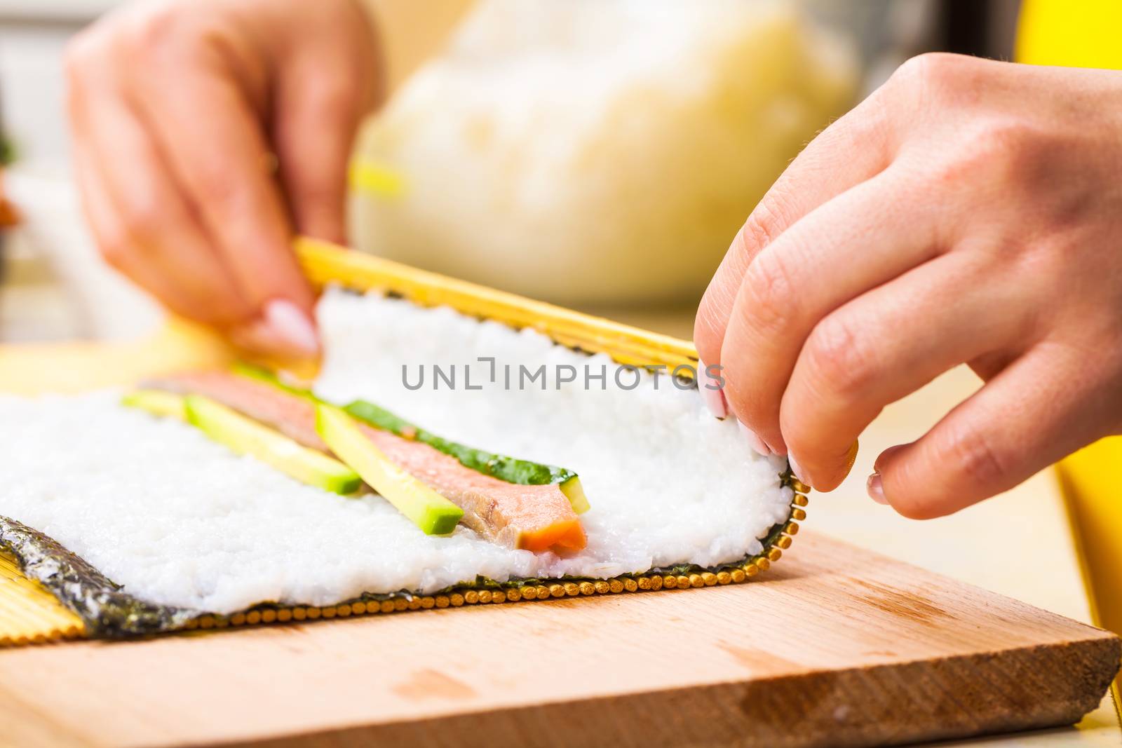 chef turns nori sheet with filling in the roll closeup