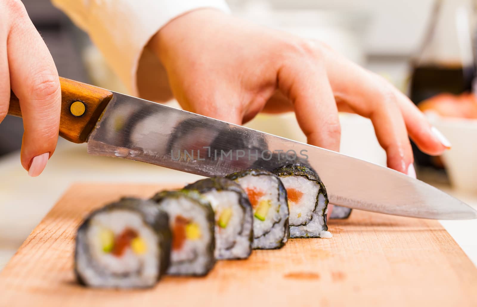 knife in hand cuts the roll closeup on a wooden board