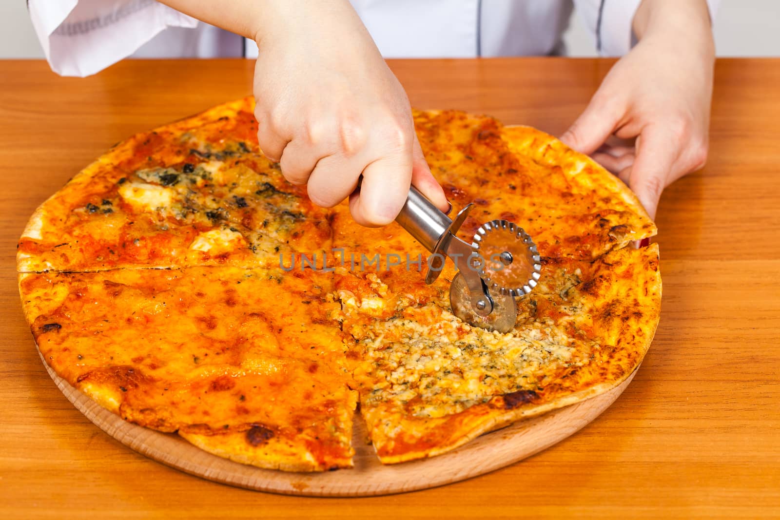 chef with knife cuts the pizza closeup