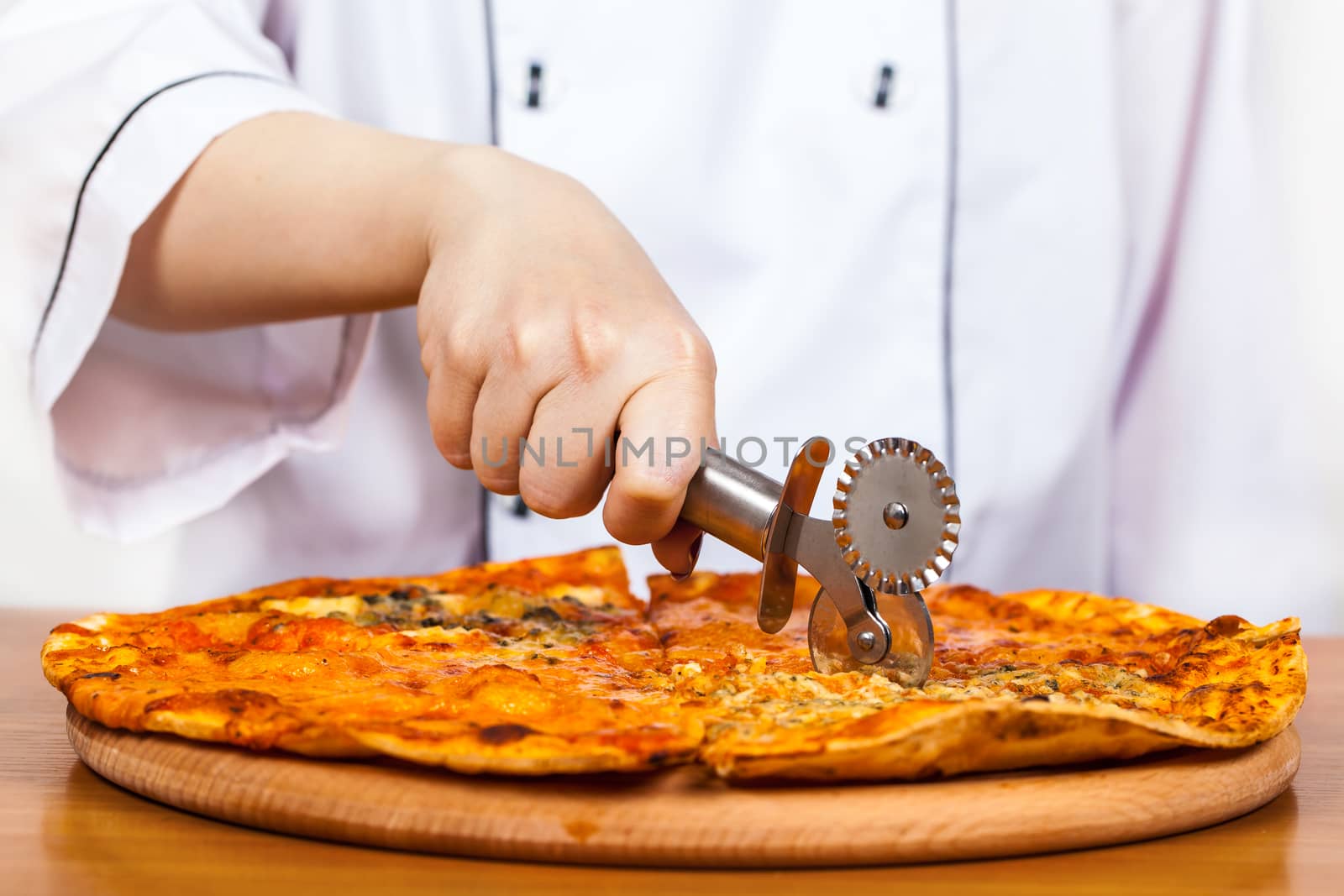 chef with knife cuts the pizza closeup