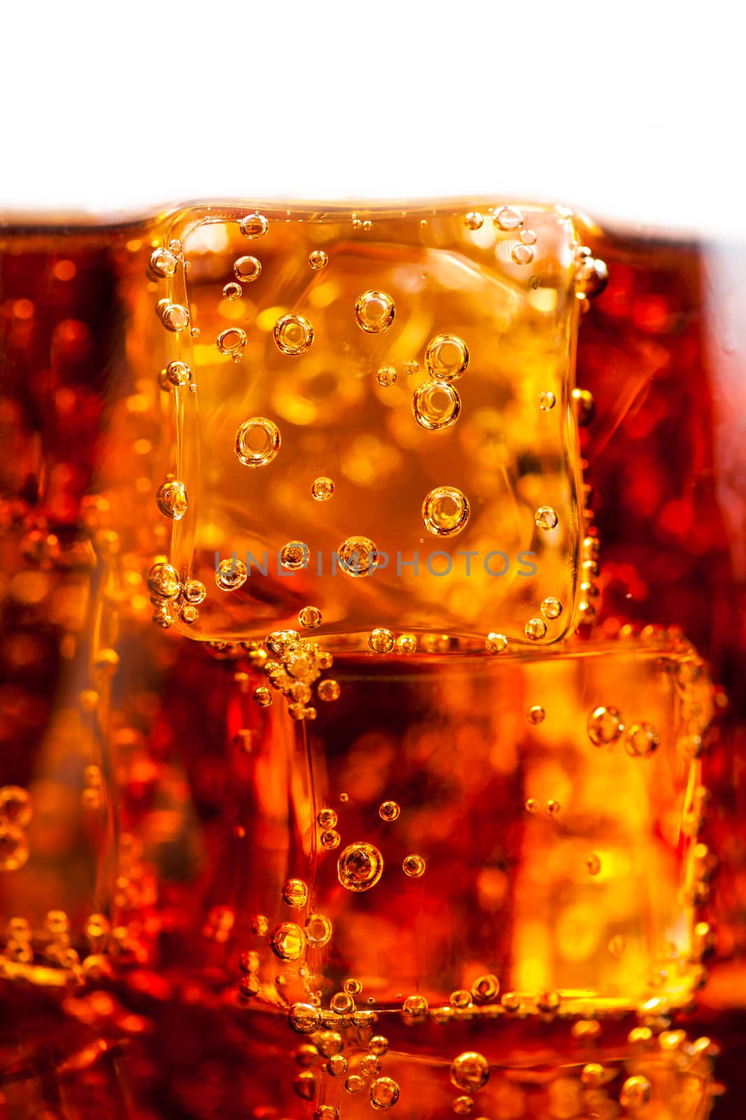 Cola with ice cubes and bubbles closeup