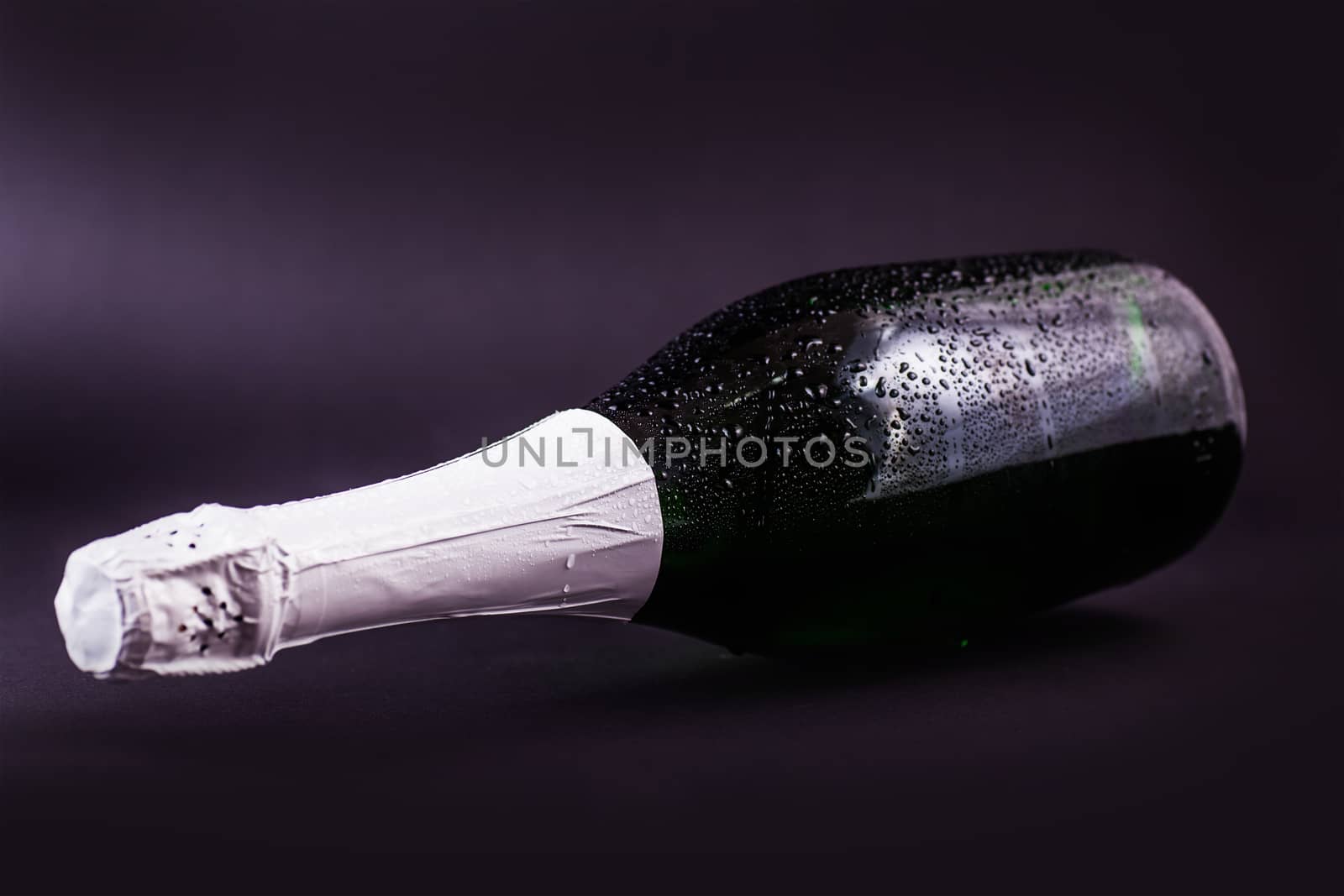 bottle of champagne in drops on a dark background