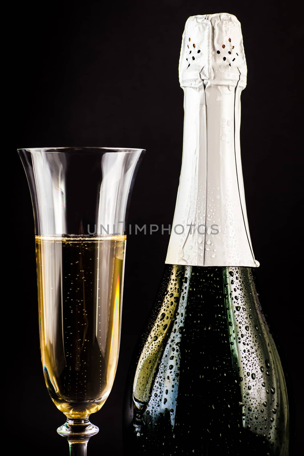 champagne bottle with a full glass on a dark background