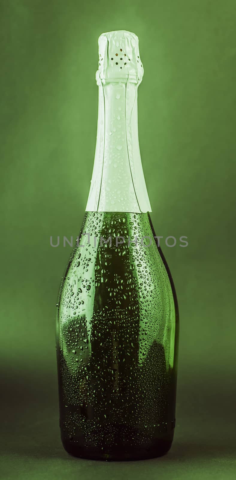 bottle of champagne in the drops on a green background