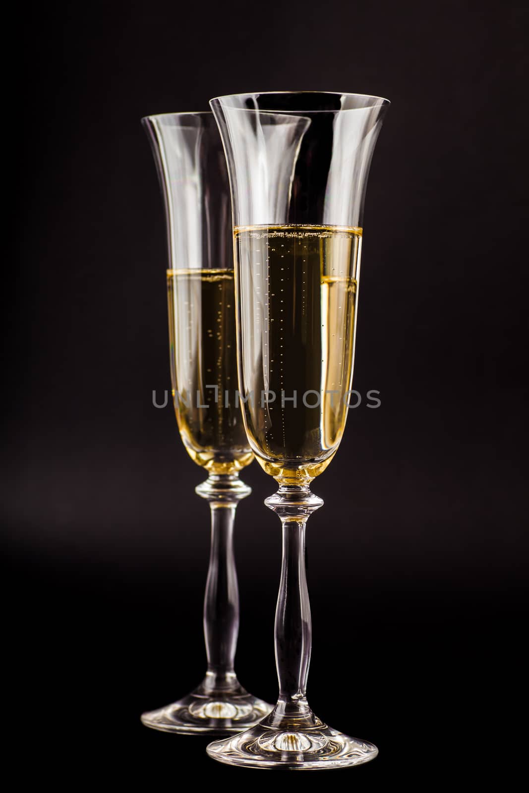 two glasses filled with champagne on a dark background