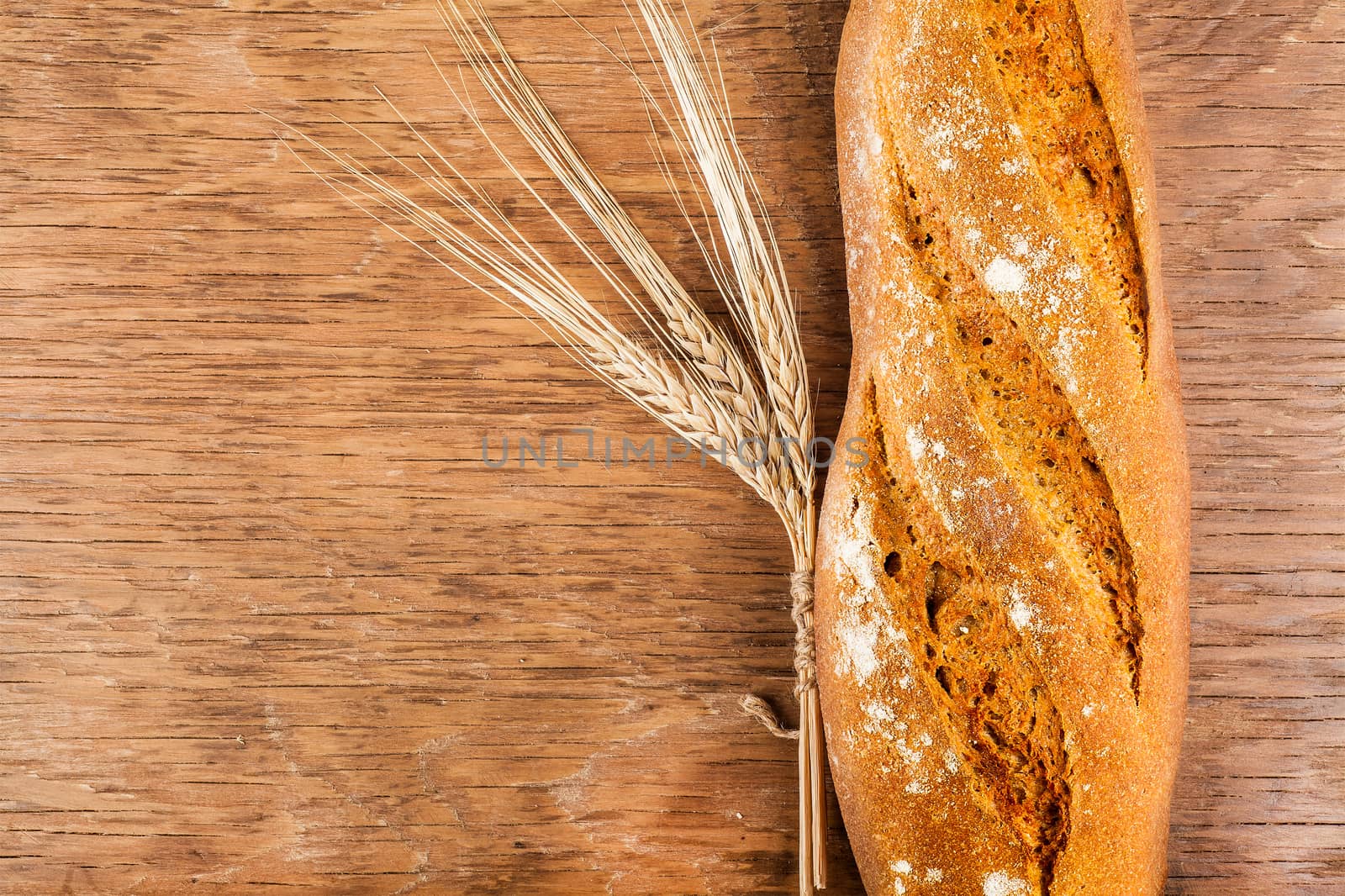 bread with ears of wheat on the wooden background