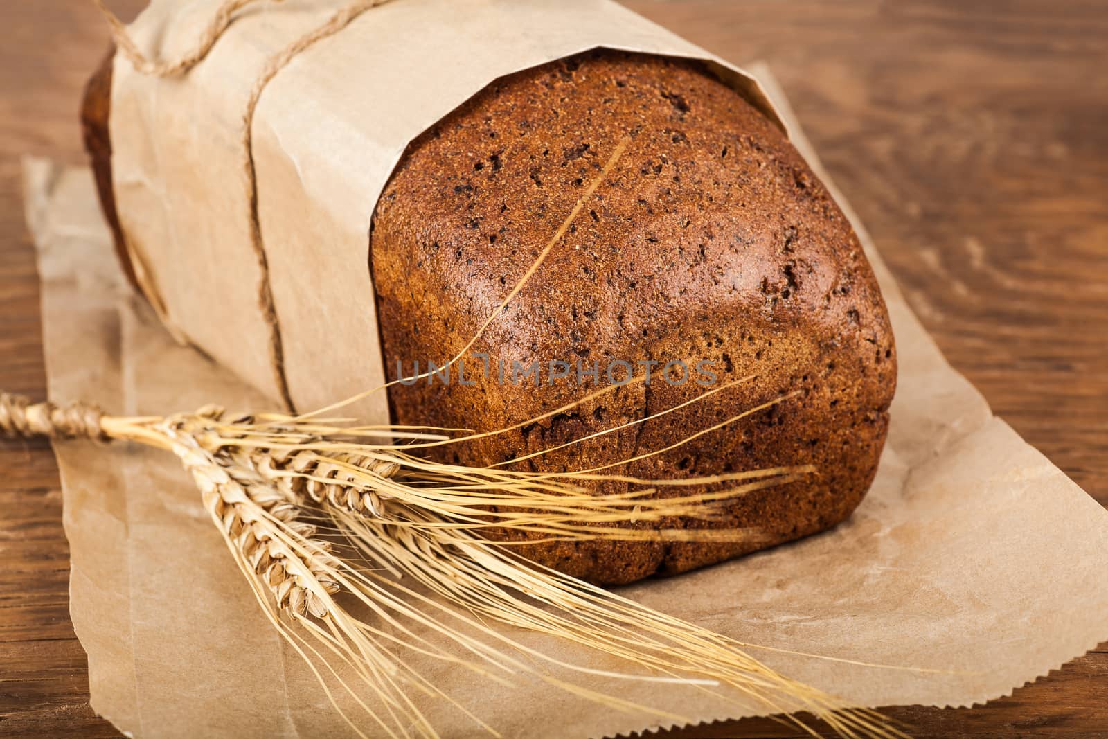 bread with ears of wheat on wooden background