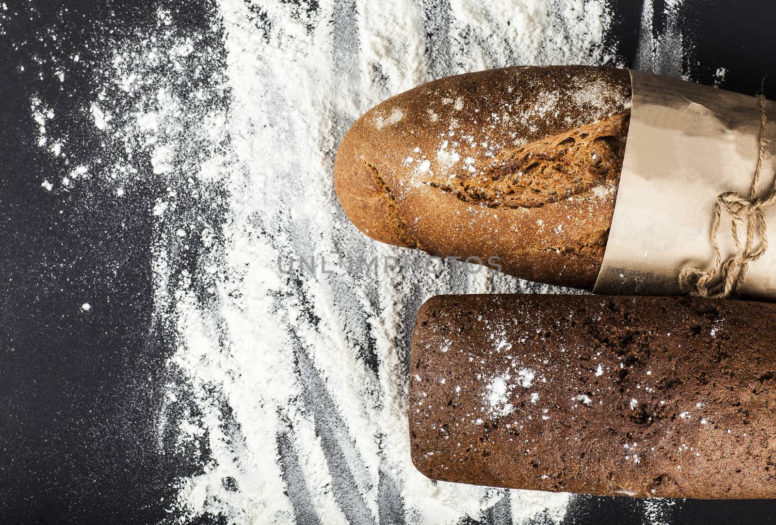 two black bread on a dark background with flour