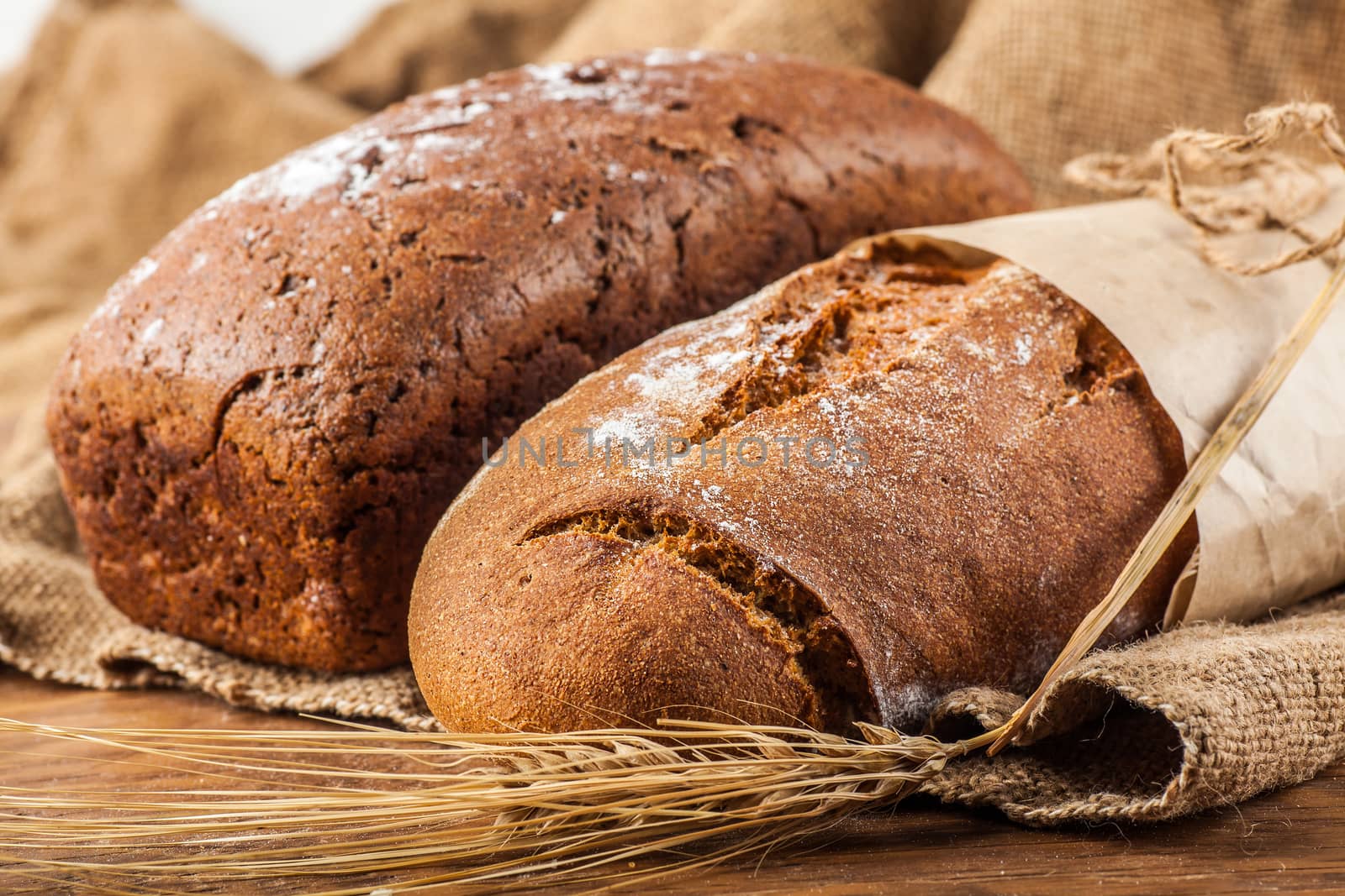 two bread with ears of wheat on the wooden background