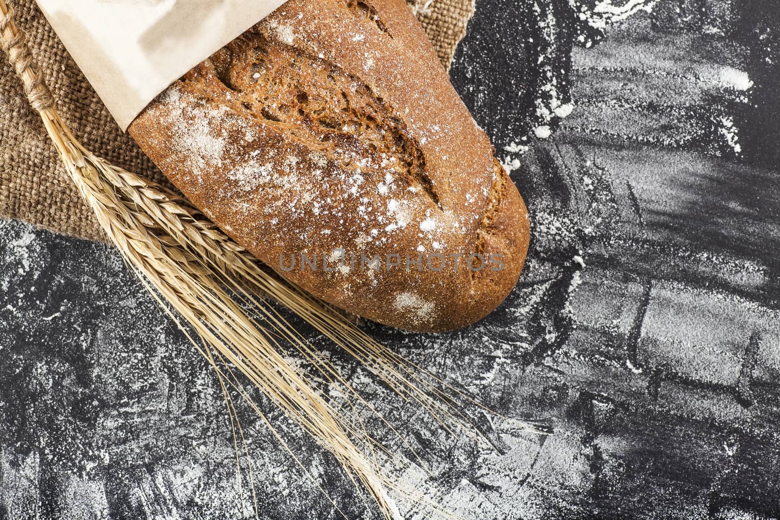 black bread with ears of wheat on a dark background