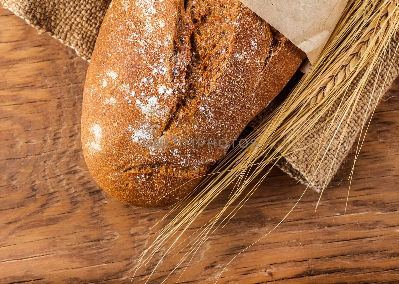 bread and ears of wheat on the wooden background