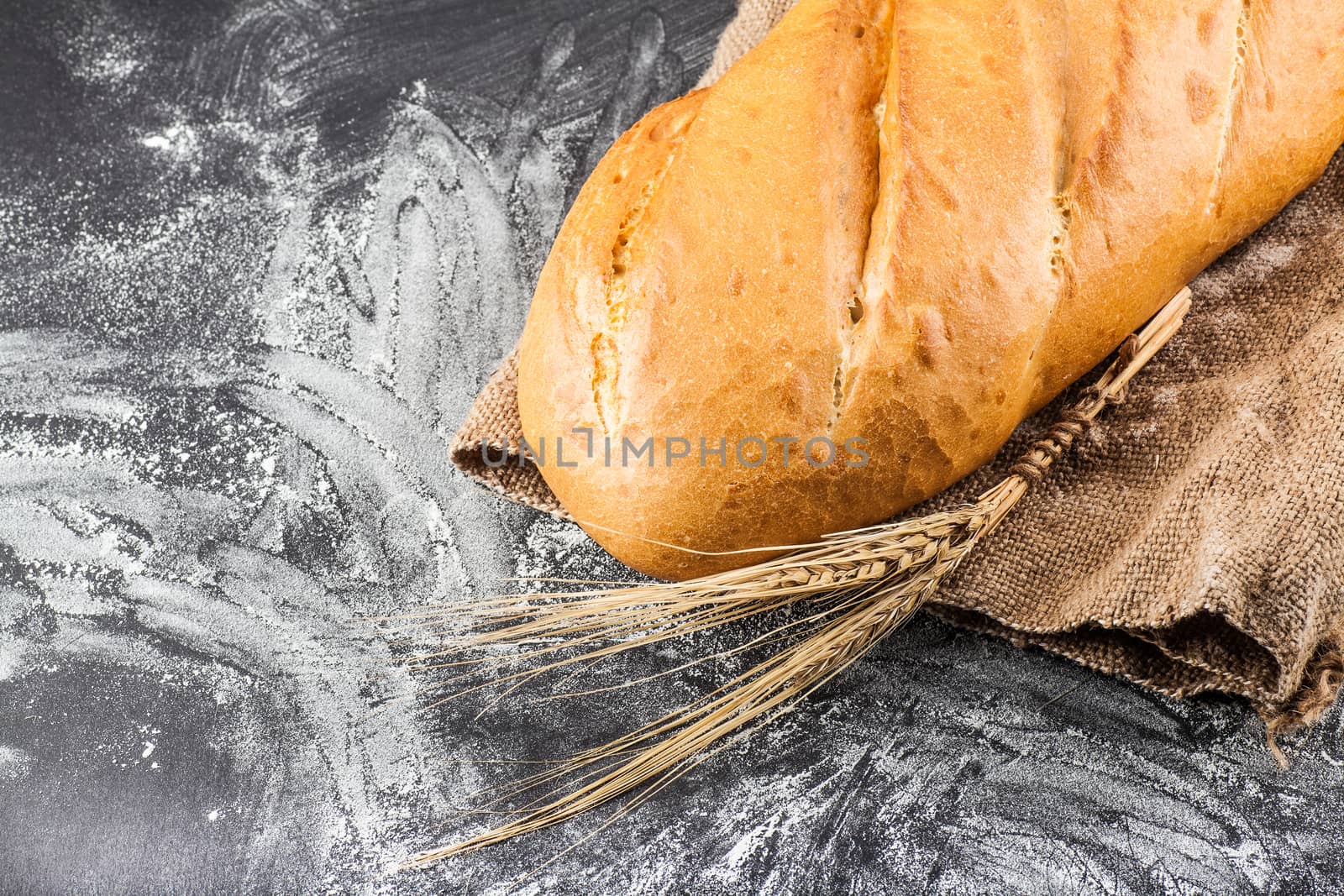 white bread with ears of wheat on a dark background