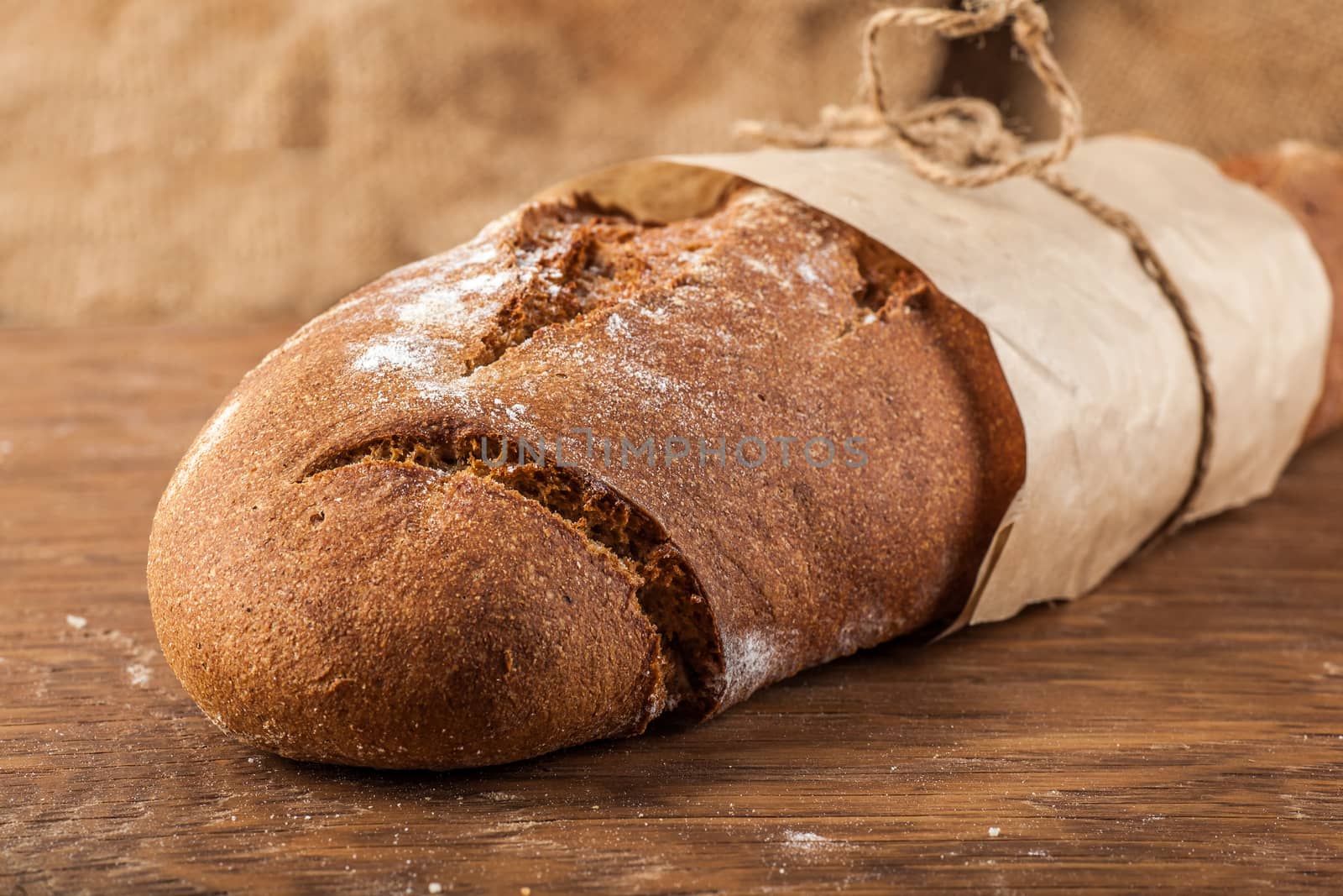 bread wrapped in paper on a wooden background