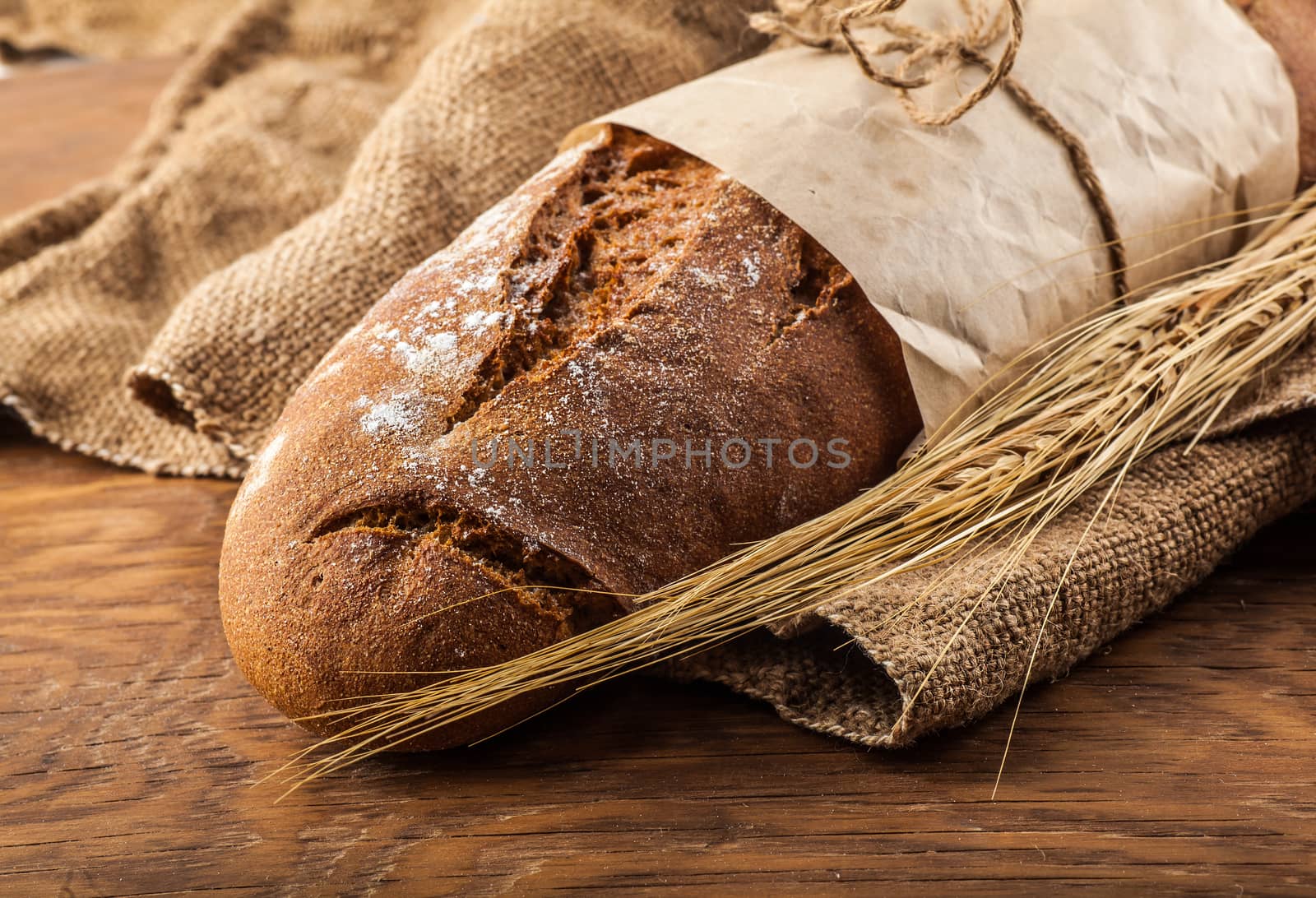 loaf of bread wrapped in paper on a wooden background