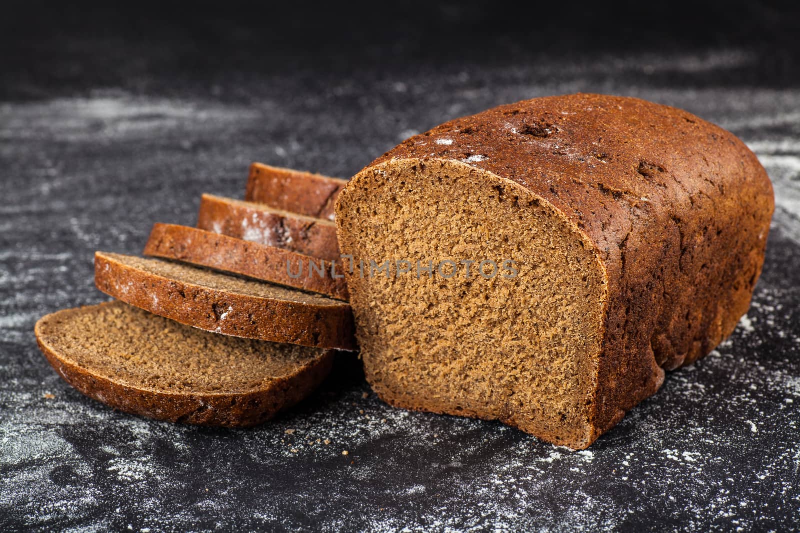 Black sliced bread on a dark background with flour