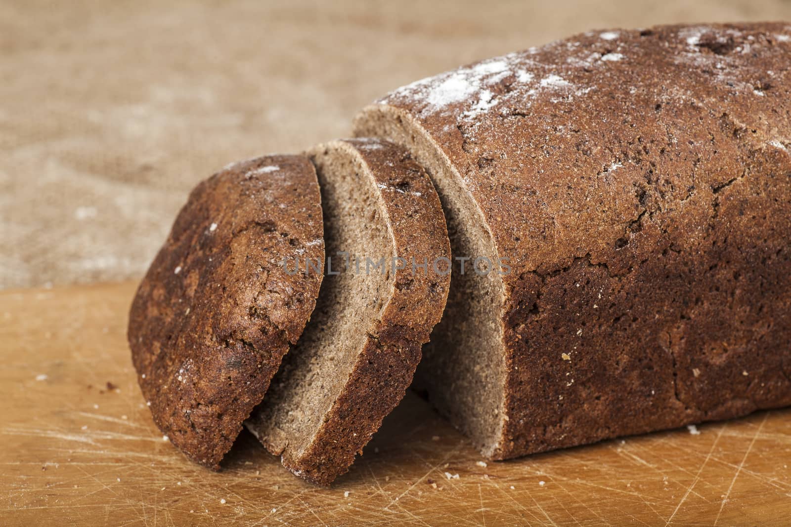 sliced loaf of black bread on a wooden board