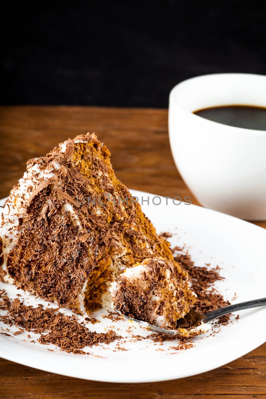 piece of chocolate cake on a plate with a spoon on a wooden background