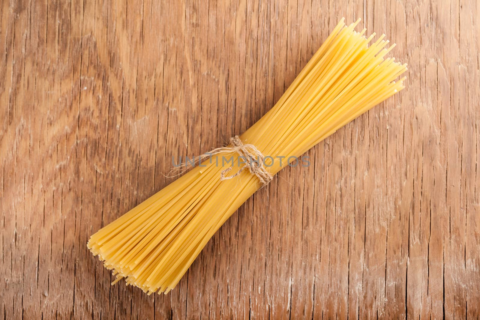 raw spaghetti tied with a rope on a wooden background