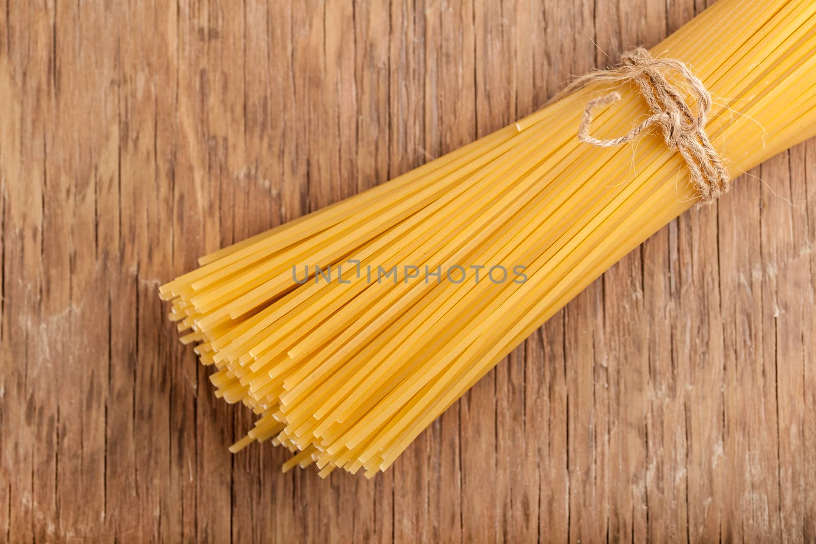 sheaf raw pasta tied with a rope on a wooden background