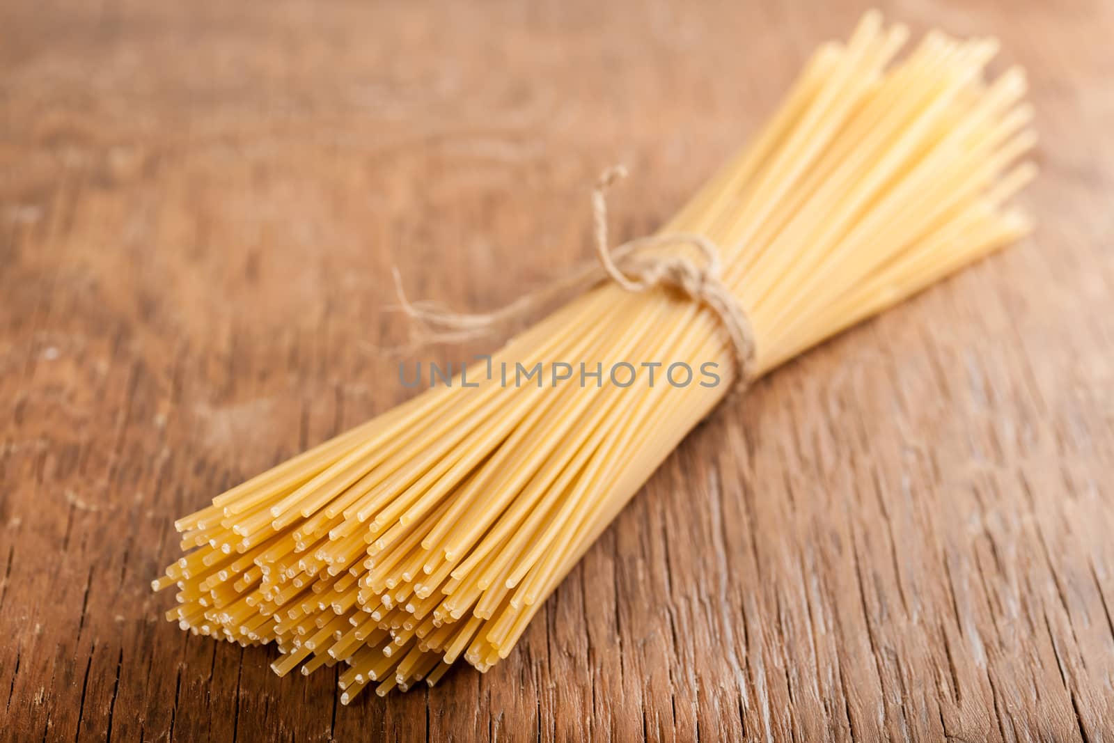sheaf raw spaghetti tied with a rope on a wooden background