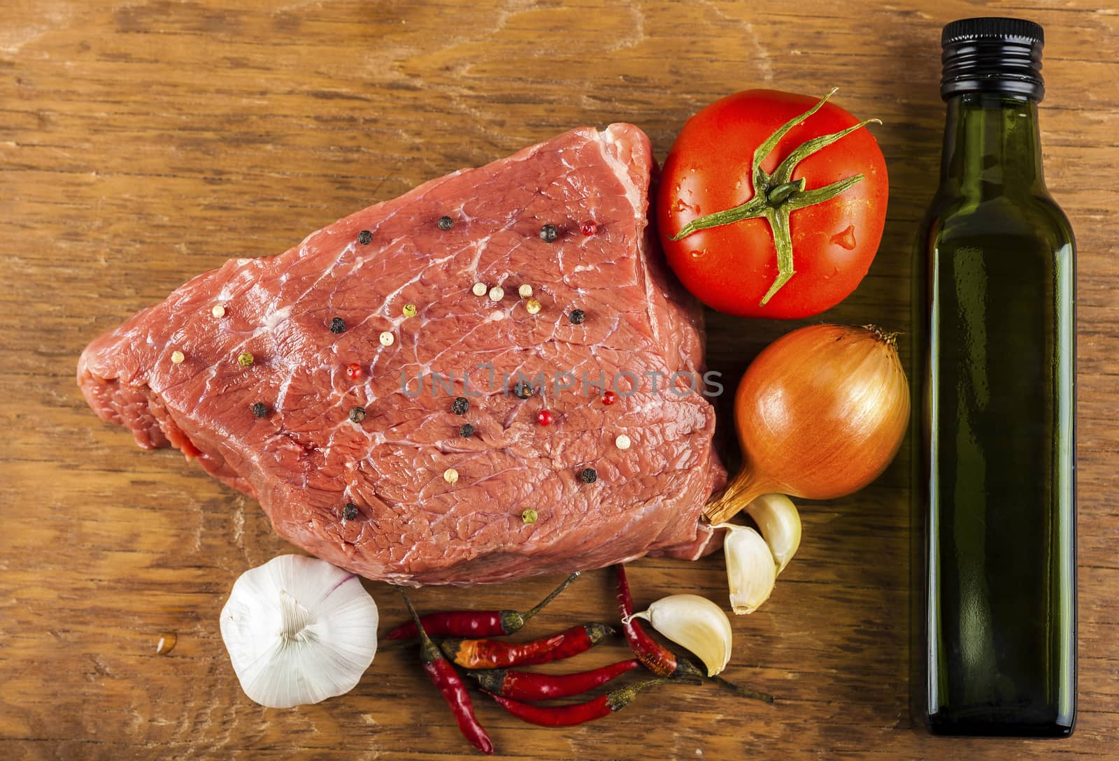 raw beef fillet with spices and vegetables on wooden background