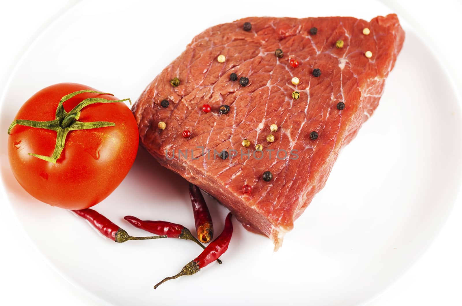 raw beef filet with spices and tomato, white background