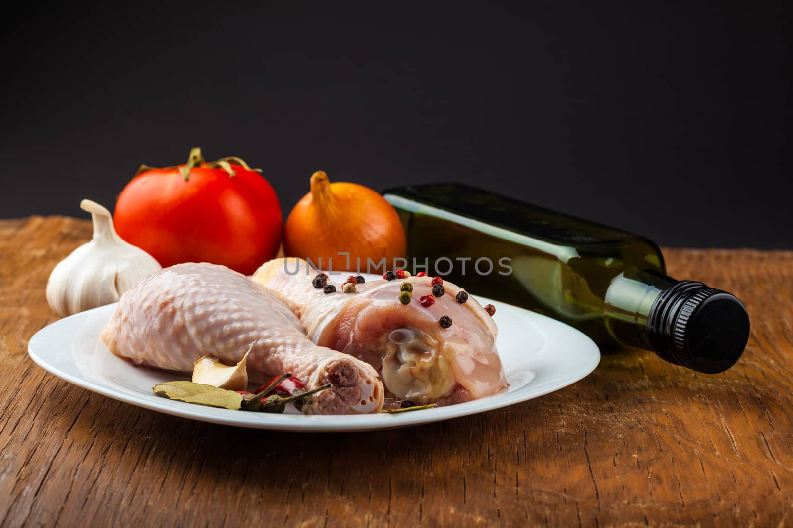 raw chicken legs on wooden board with spices, dark background
