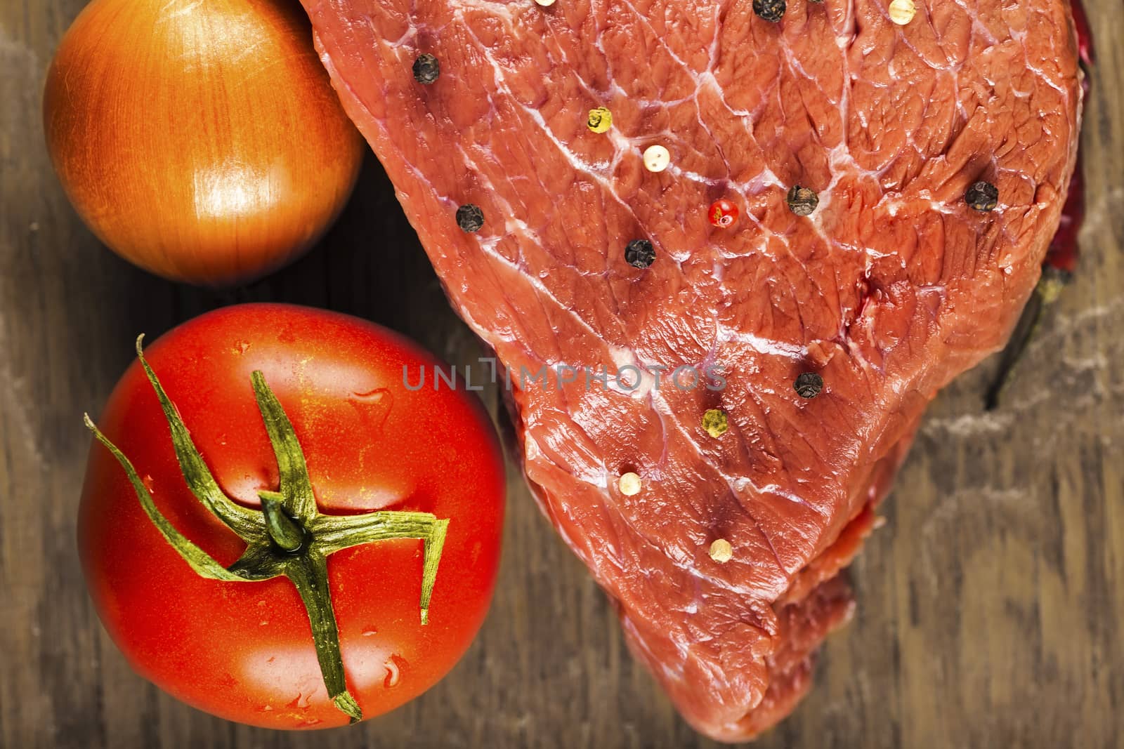 fillet of beef with spices and vegetables on wooden background