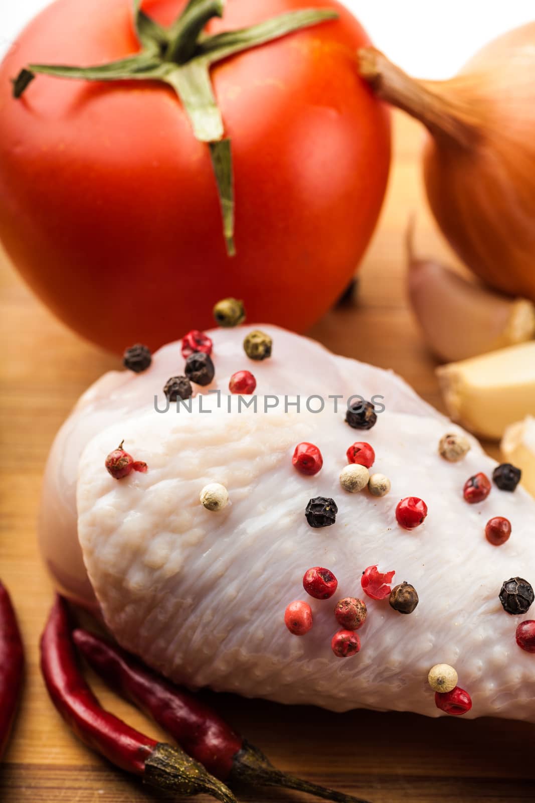 chicken leg on a wooden board with spices and vegetables