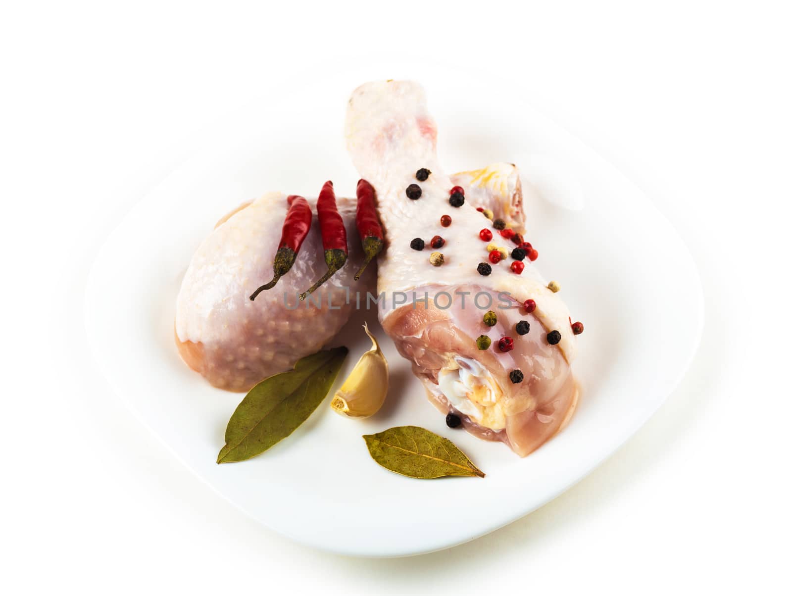 raw chicken feet on the plate with spices, white background
