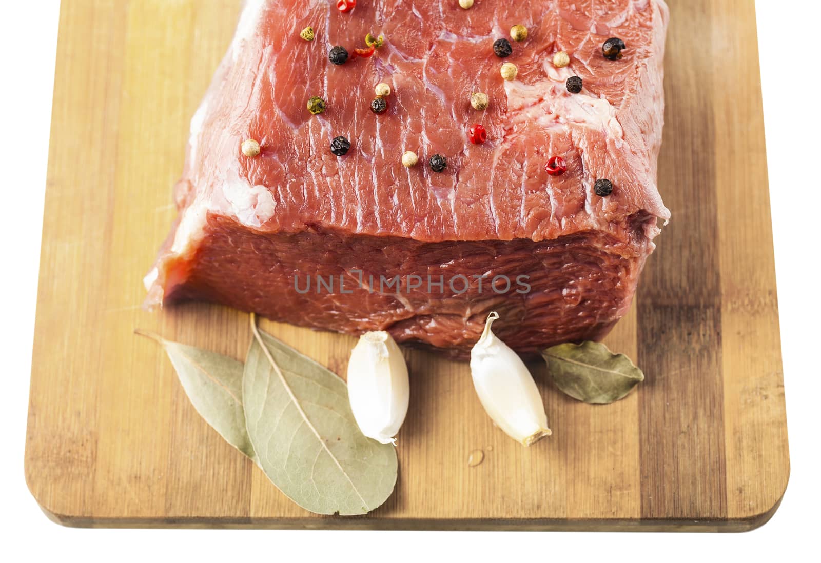 beef filet with spices on a wooden board, white background