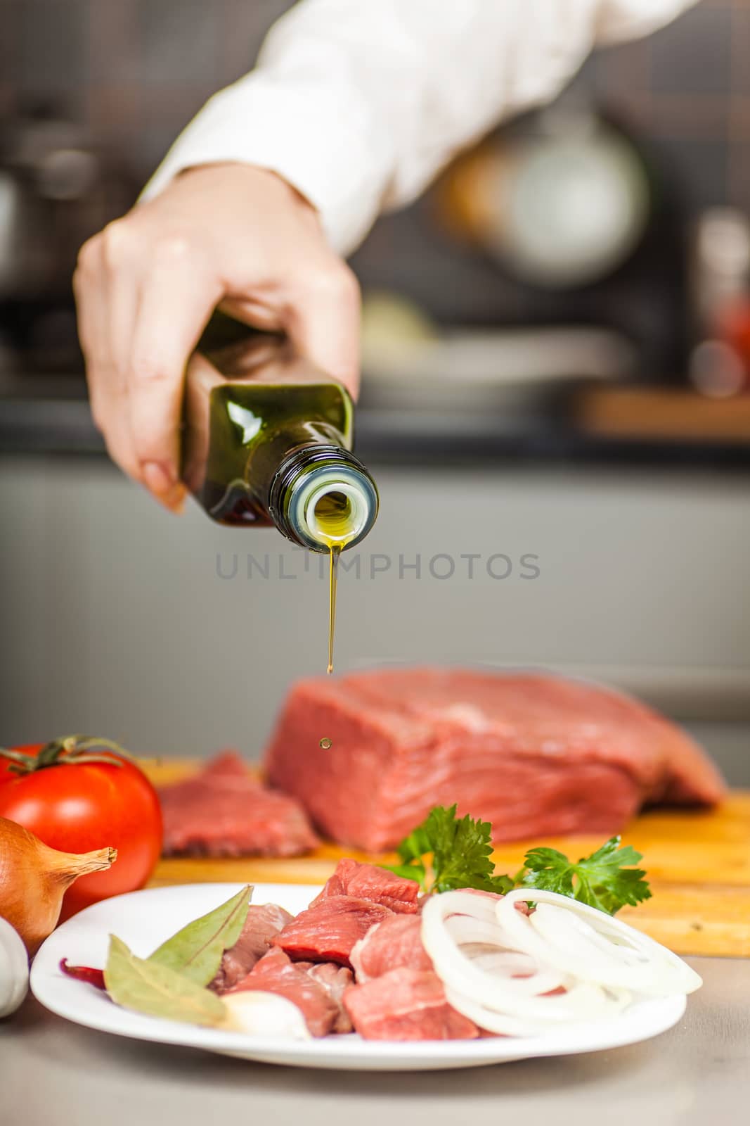 Chef pours olive oil on beef fillet