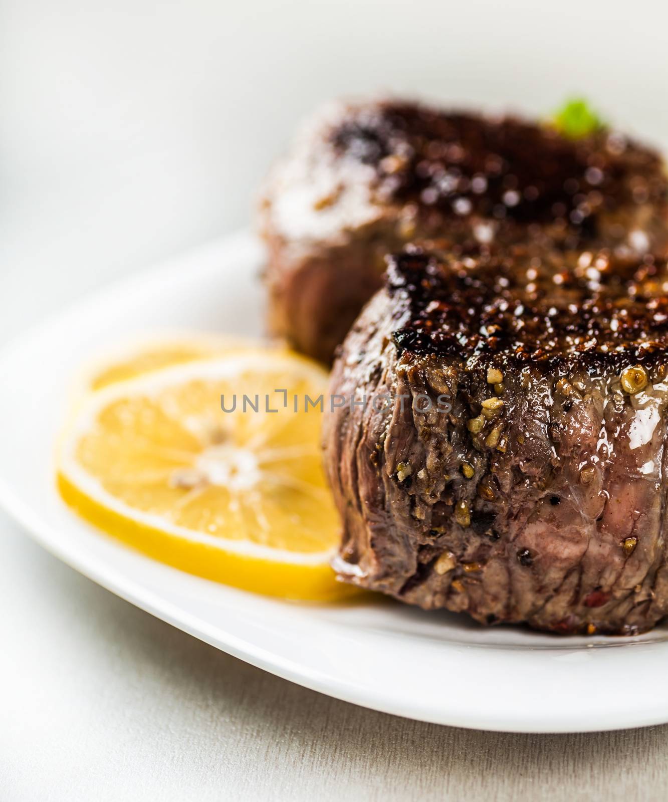 freshly prepared medallion on a plate with lemon wedges closeup