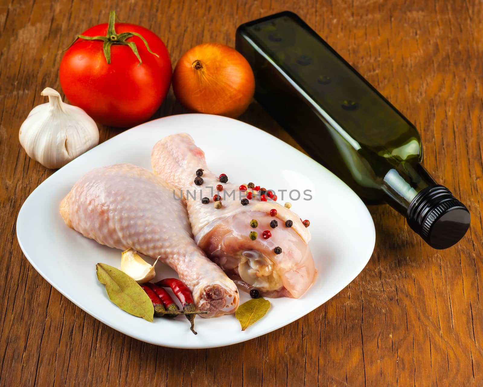 raw chicken legs on the plate with spices, wood background