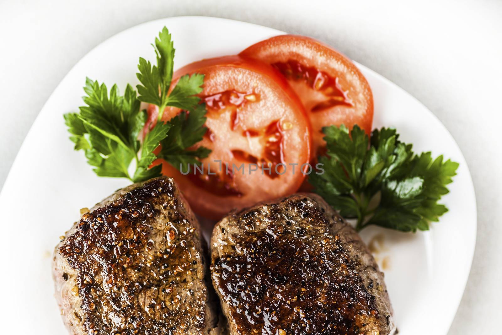 freshly made medallion on a plate with slices of tomato