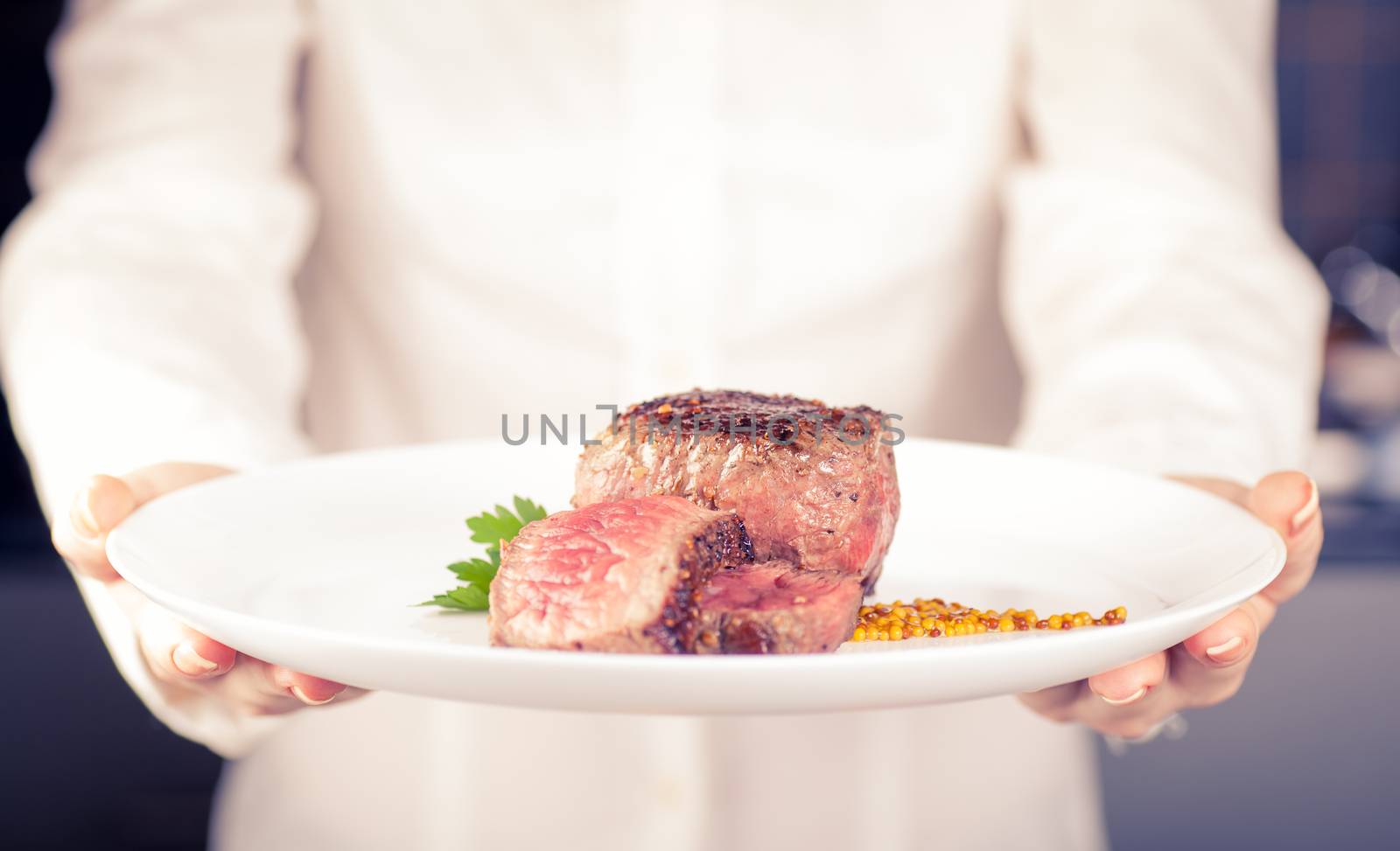 Chef keeps a dish of medallions in hands
