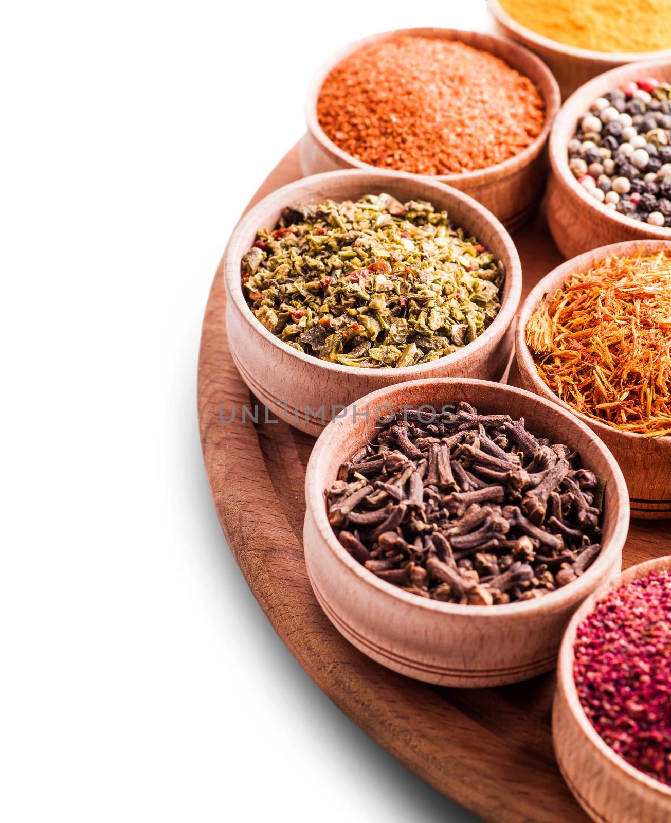 assorted spices in a wooden bowl close-up on white background