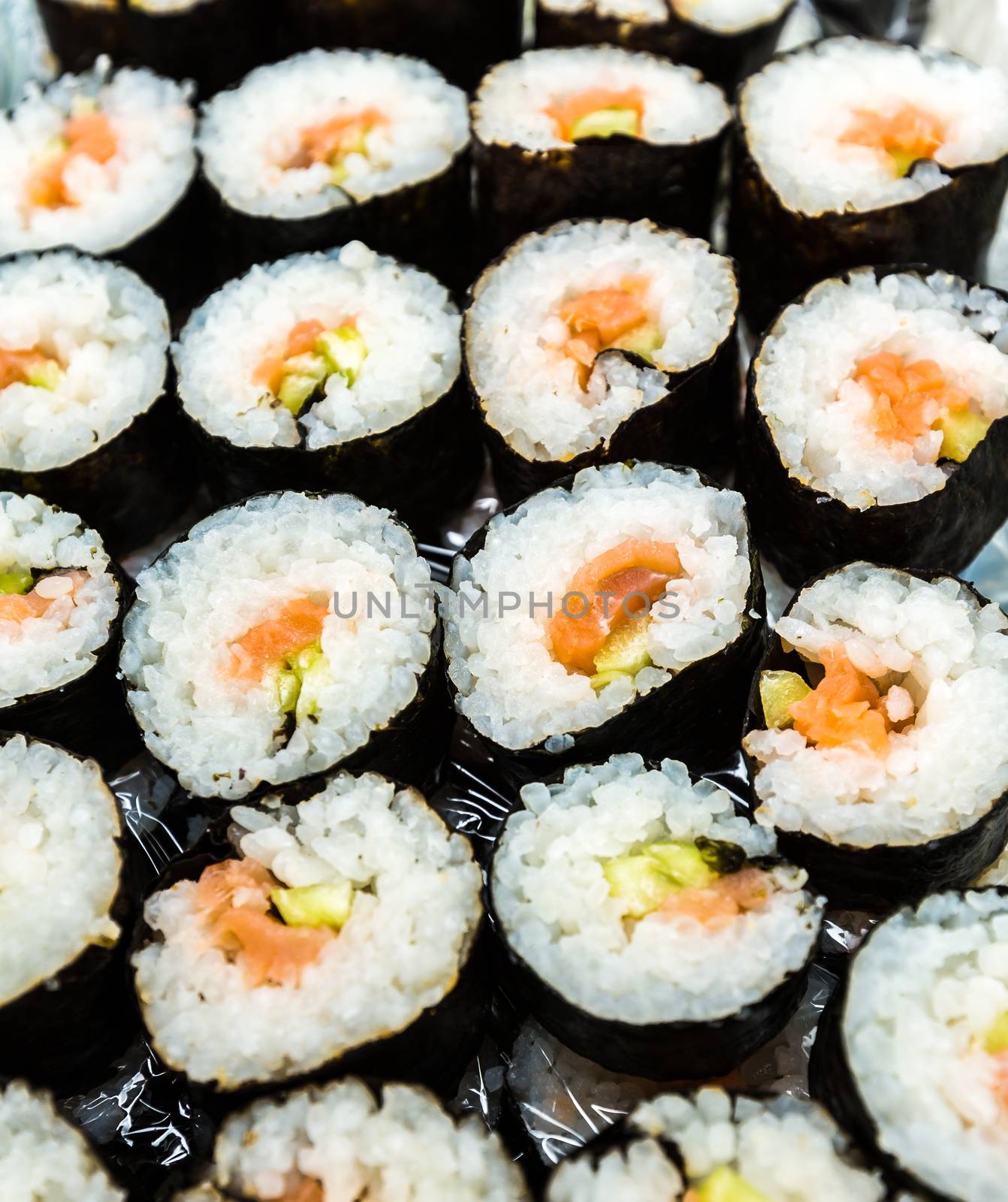 background of freshly prepared sushi rolls laid out in a row