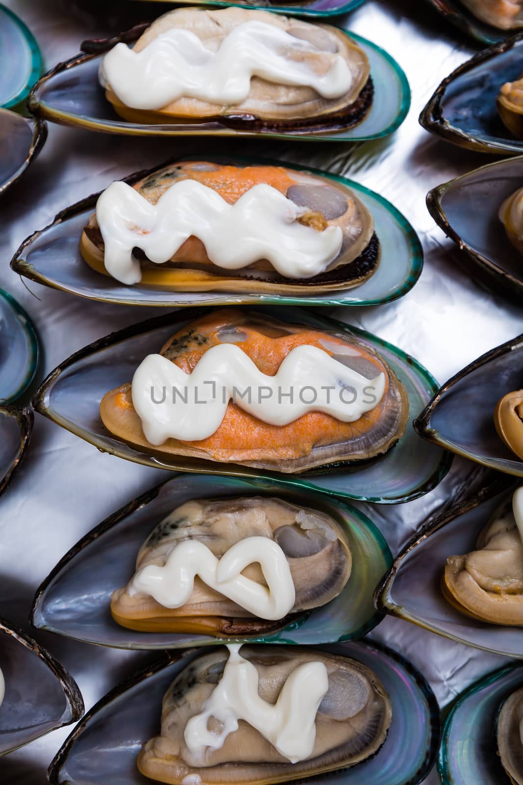 mussels in shells lying in a row with spices