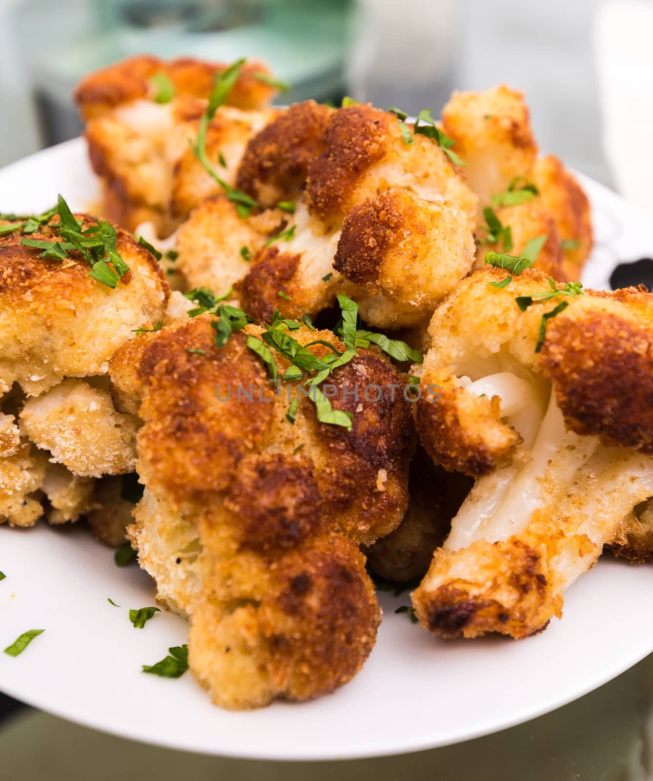 breaded and fried a cauliflower lying on a plate with greens