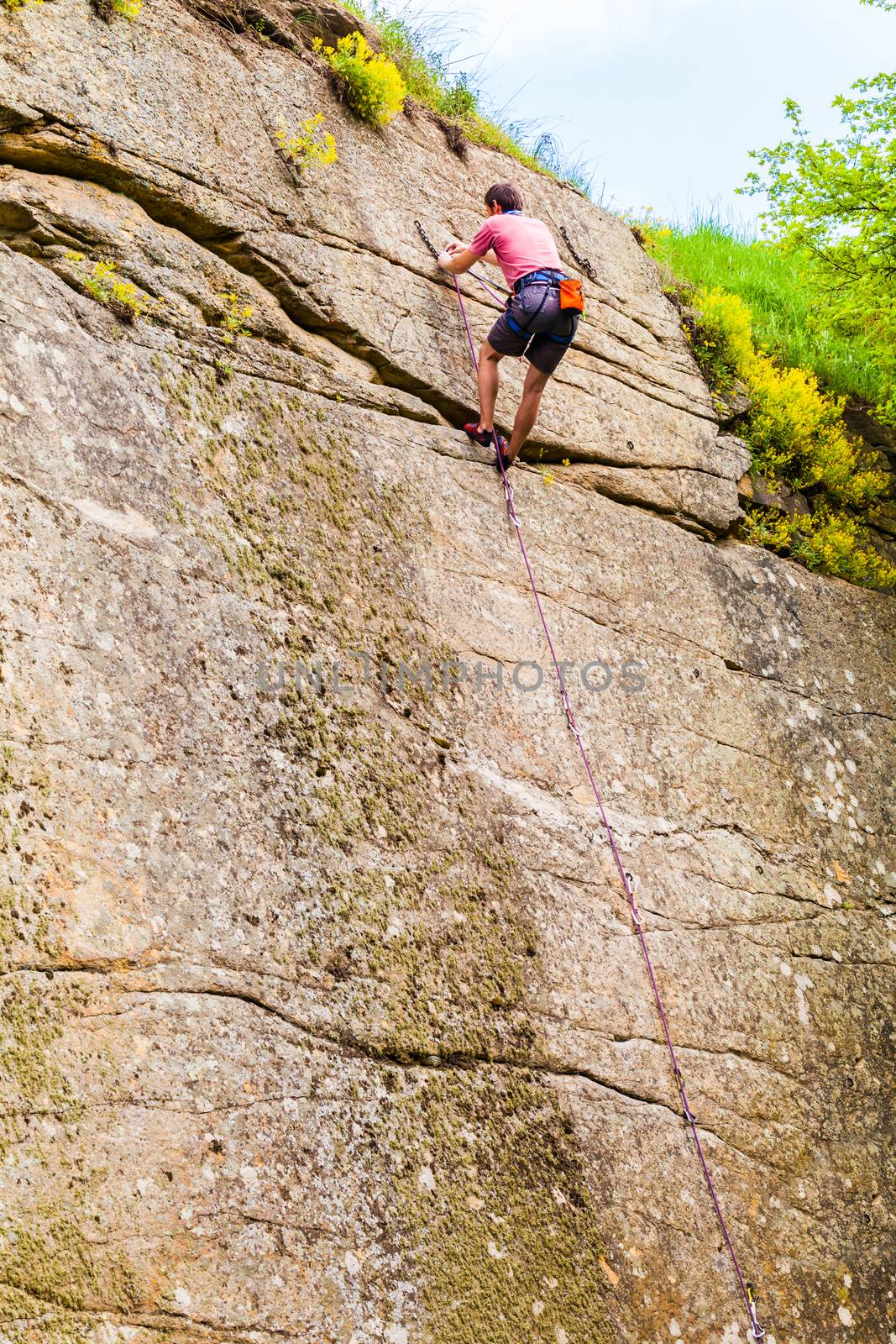 male athlete mountain climber climbing up a cliff