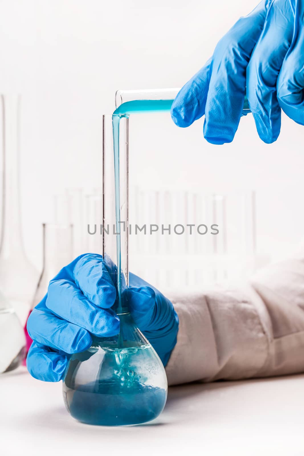 laboratorian pours reagent in the flask on a white background
