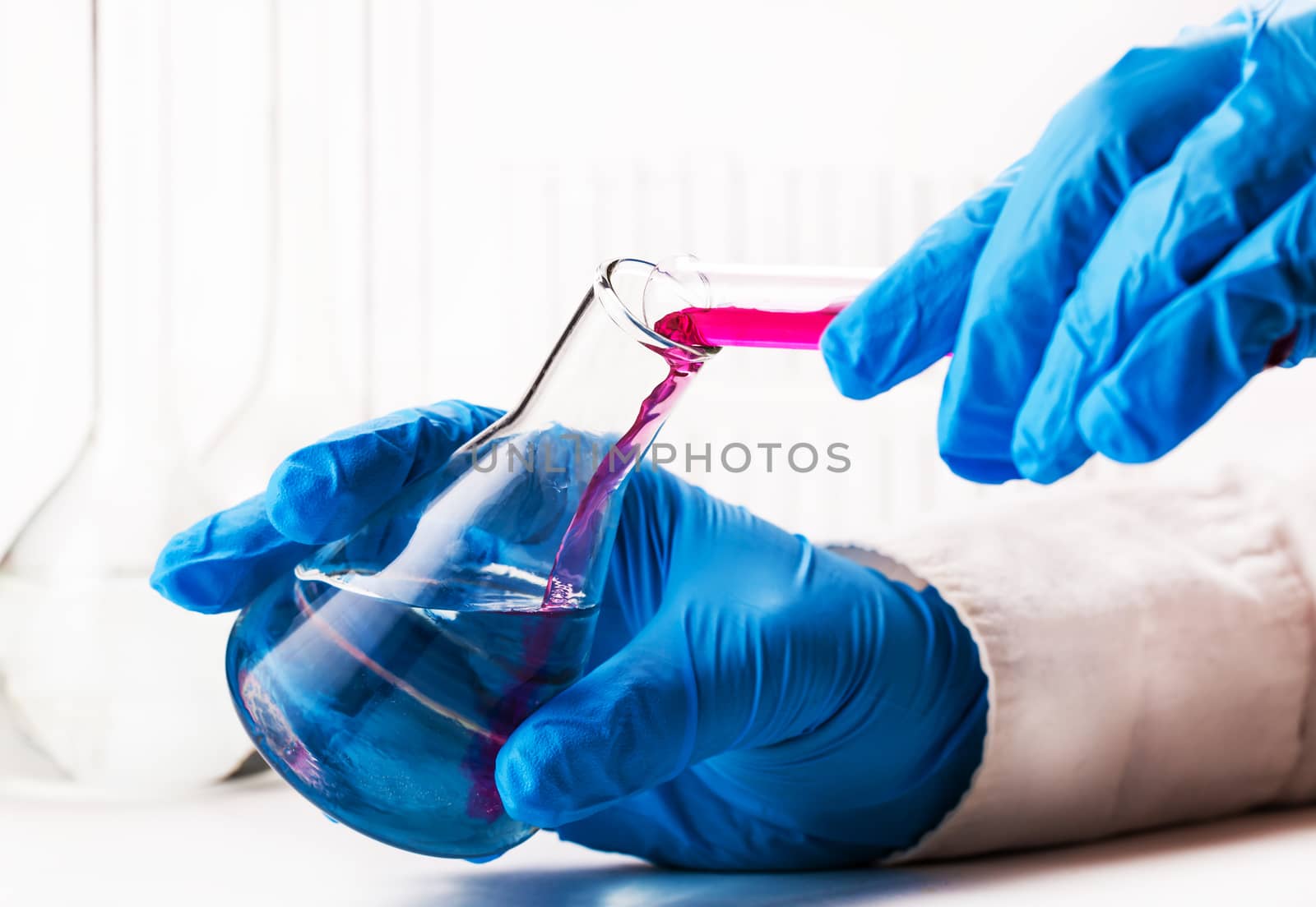 assistant reagent pouring into the flask on a white background