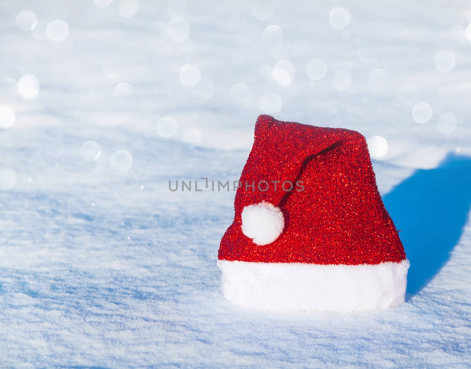 Christmas cap with bubo lying on a snowy background
